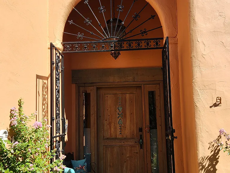 Stunning wrought iron entry gate and custom front door.