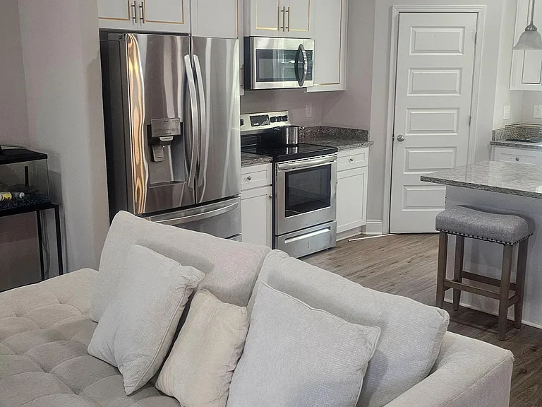 Open-concept kitchen with stainless steel appliances, ample cabinetry, and a breakfast bar that flows into the living area.