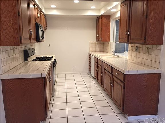 All white tile on floor and cabinets, all wood cabinets with