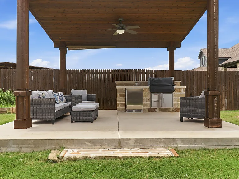 Custom Outdoor Pavilion featuring a wood-finish ceiling, ceiling fan, and an outdoor kitchen with built-in stainless steel appliances and stone facade