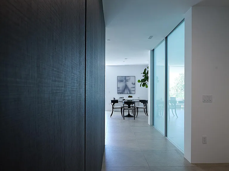 Sleek Transitional Hallway with Architectural Contrast _ This striking passageway inside the one-bedroom residence blends bold dark paneling with soft natural light, leading seamlessly into the open dining area.