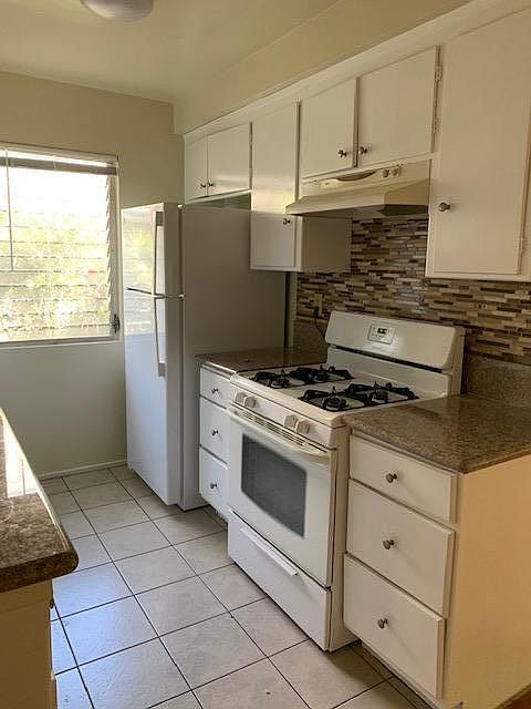 kitchen with counter top, hood, closets, oven and refrigerator