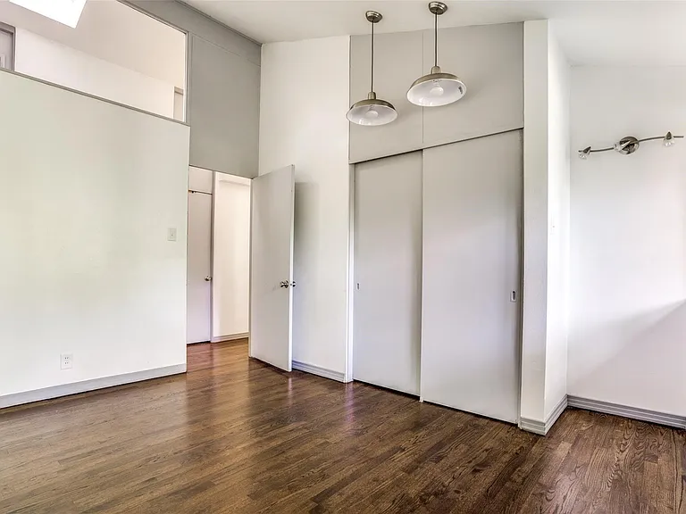 Interior space featuring wood-finish flooring, white walls, and a high ceiling