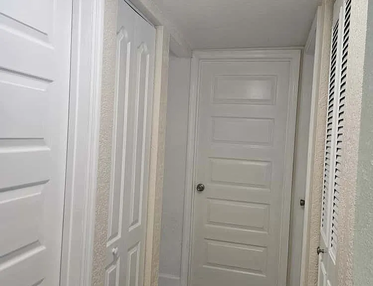 Hallway with doors leading to bathroom, linen closet, A/C and W/H closet, laundry area for 24" stackable washer/dryer, and bedrooms