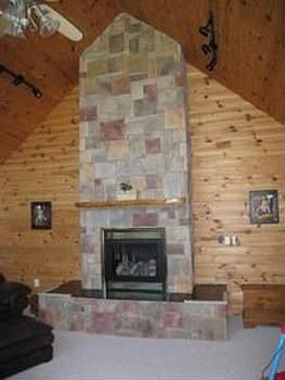 Full wall stone fireplace with vaulted ceiling made of red pine.