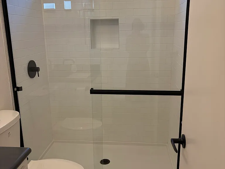 A window above the shower lets in sunlight. The shower has a rainshower-style showerhead, plus there is a built-in nook for your shampoo!