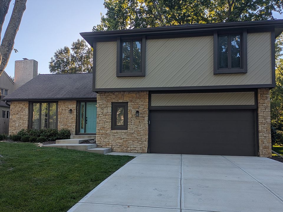 Beautiful front exterior with stone accents, modern garage door, and inviting teal entry.