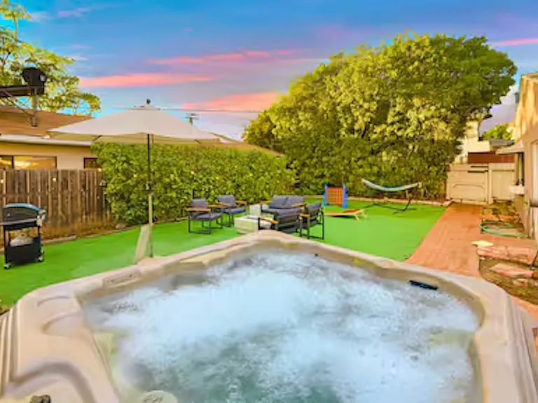 Enjoy the private outdoor space featuring a spacious hot tub that seats 6_8 guests and a cozy fire pit, perfect for relaxing after a beach day. The area also includes a barbecue grill and lawn games, ideal for outdoor dining and fun.