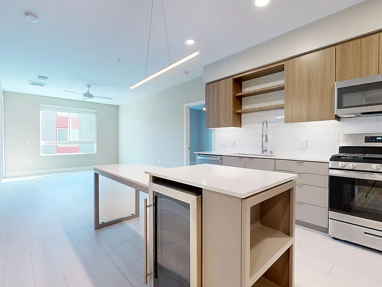 Apartment Kitchen with Stainless Steel Appliances, Dining and Living Room with Wood-Style Flooring.