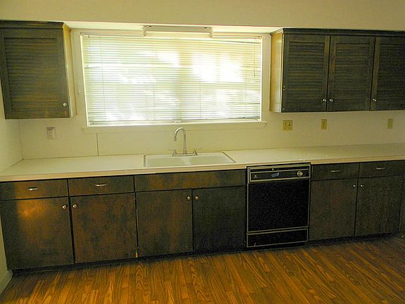 Kitchen is complete with dual kitchen sinks, dishwasher, wood floor panels, lots of cabinets and counter space ideal for any iron chef.