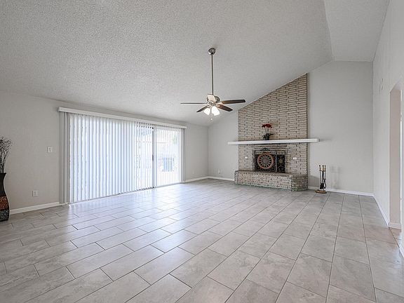 The great room boasts vaulted ceilings, a wood burning fireplace, and access to the back patio. Slider has security film.