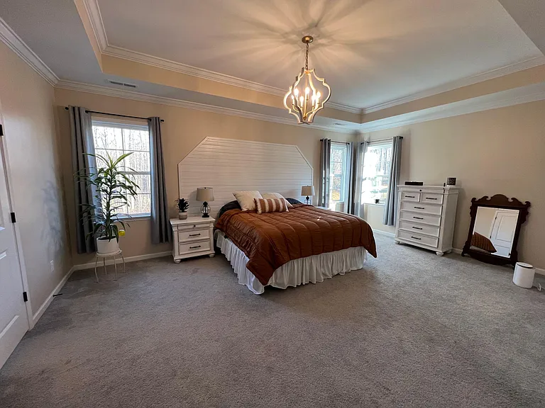 Expansive primary suite with French doors and tray ceilings