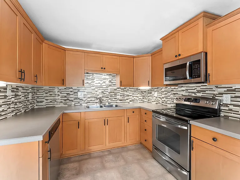 Kitchen with updated cabinets, stainless steel appliances & mosaic tile backsplash.