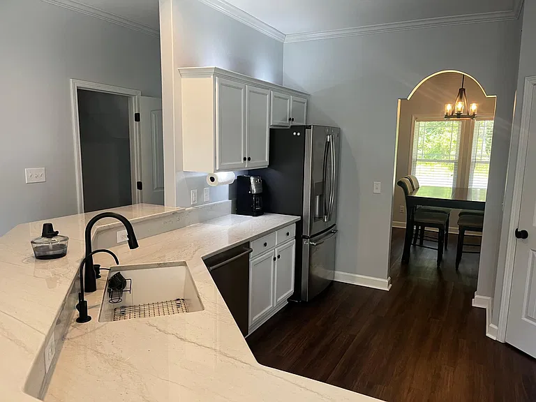 Bright kitchen with quartzite countertops, farmhouse-style sink, stainless steel appliances, and direct access to the dining area.