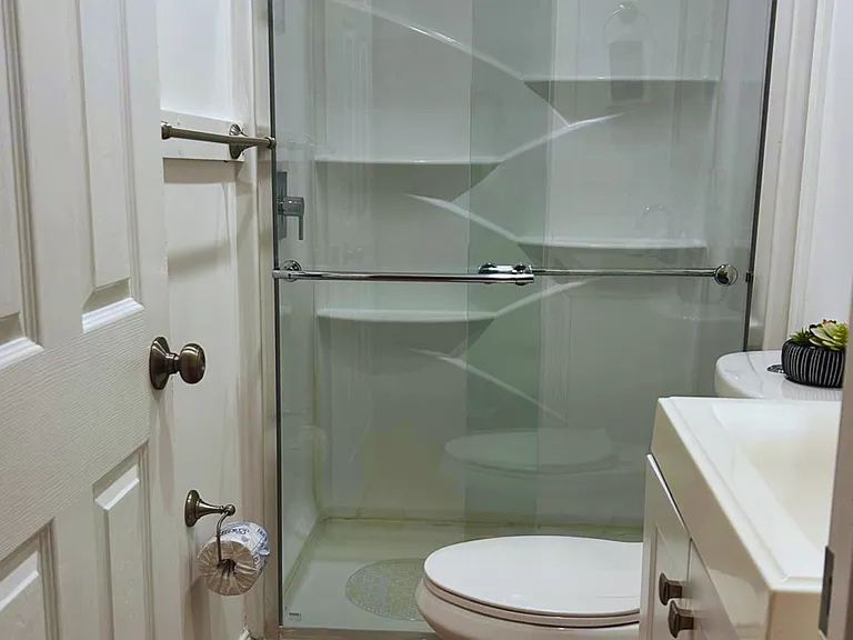 Well-appointed bathroom equipped with a toilet, shower, mirror, and storage cabinet