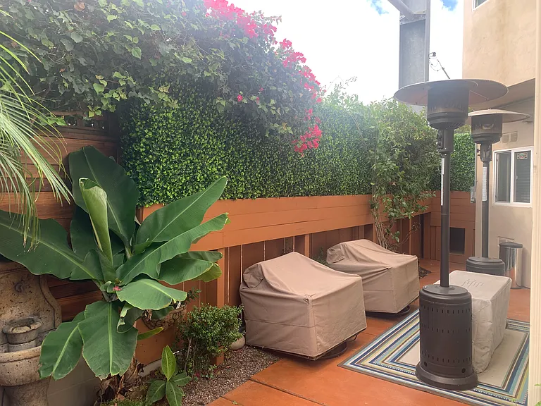 Outside Fenced Tropical Patio with Wicker Furniture, Heaters, Fire Pit, & Hot Tub