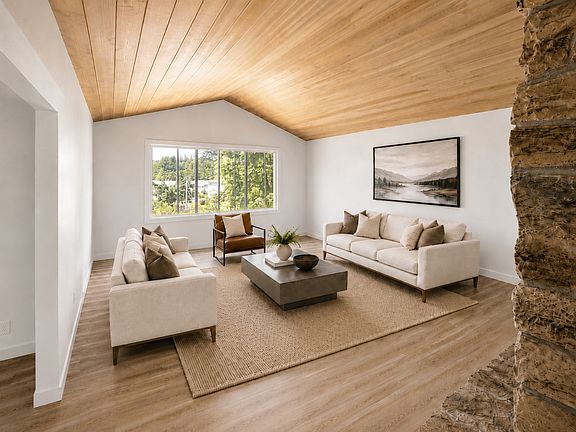 Grand family room with stone fireplace and cedar ceiling and plenty of light
