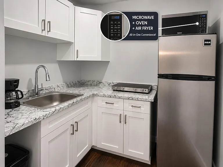 Efficient kitchen with shaker cabinetry, stone-look counters, stainless refrigerator, and a versatile microwave/air-fryer uni