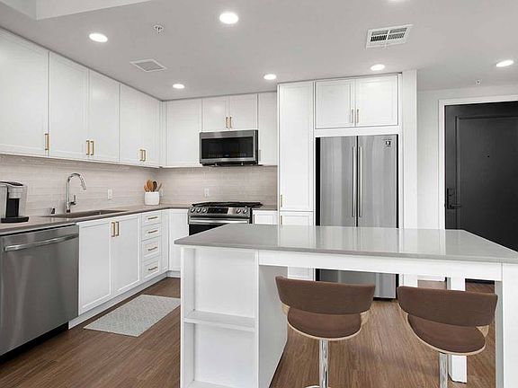 Building A Upgrade Design 1 kitchen with quartz countertops, stainless steel appliances, backsplash and island