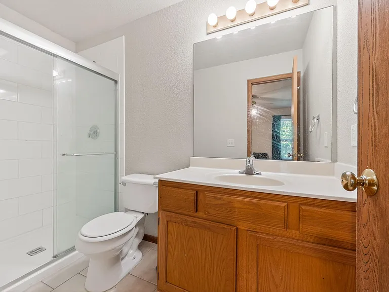 Full bathroom with a tub/shower combo, large vanity with storage, and an oversized mirror with ample lighting.