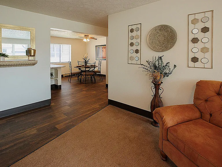Inviting open-concept living space showcasing a cozy seating area, elegant hardwood floors, and a stylish dining nook with natural light.