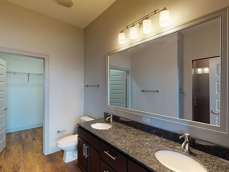 Apartment bathroom with wood-style flooring and double sinks.