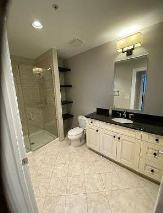 Bathroom with tile and granite. Shelving for additional storage.