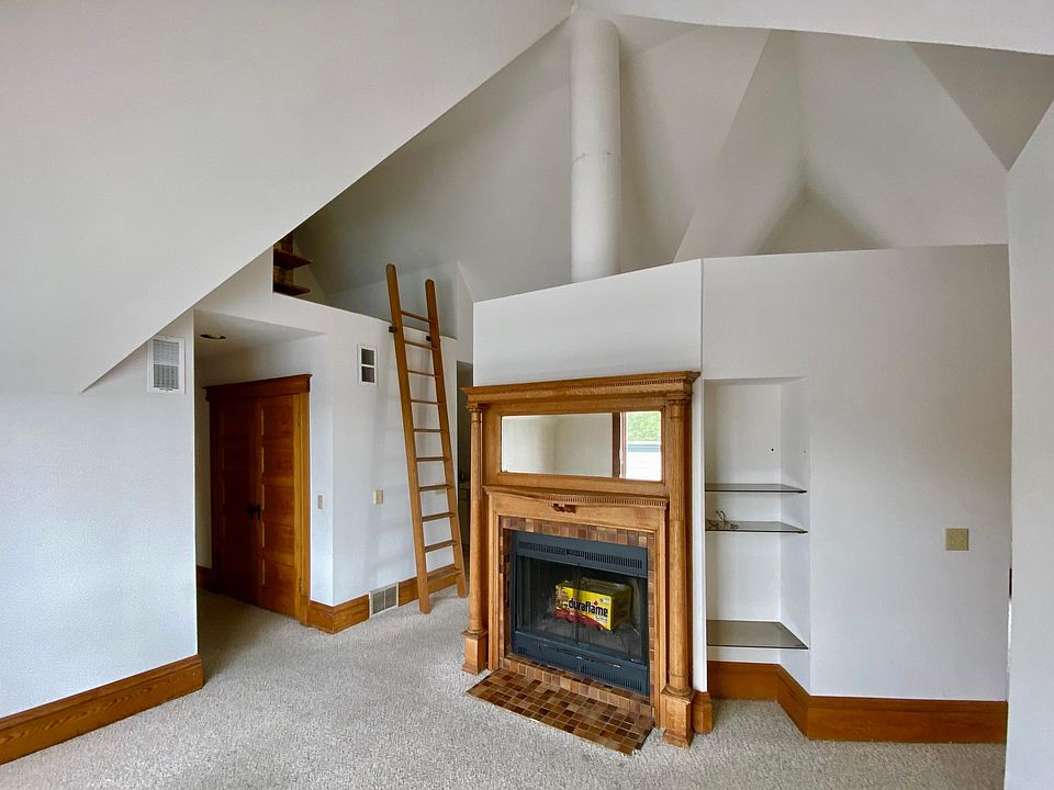 Living room w/fireplace and ladder to loft. Hall to left has laundry closet; leads to bath, bedroom