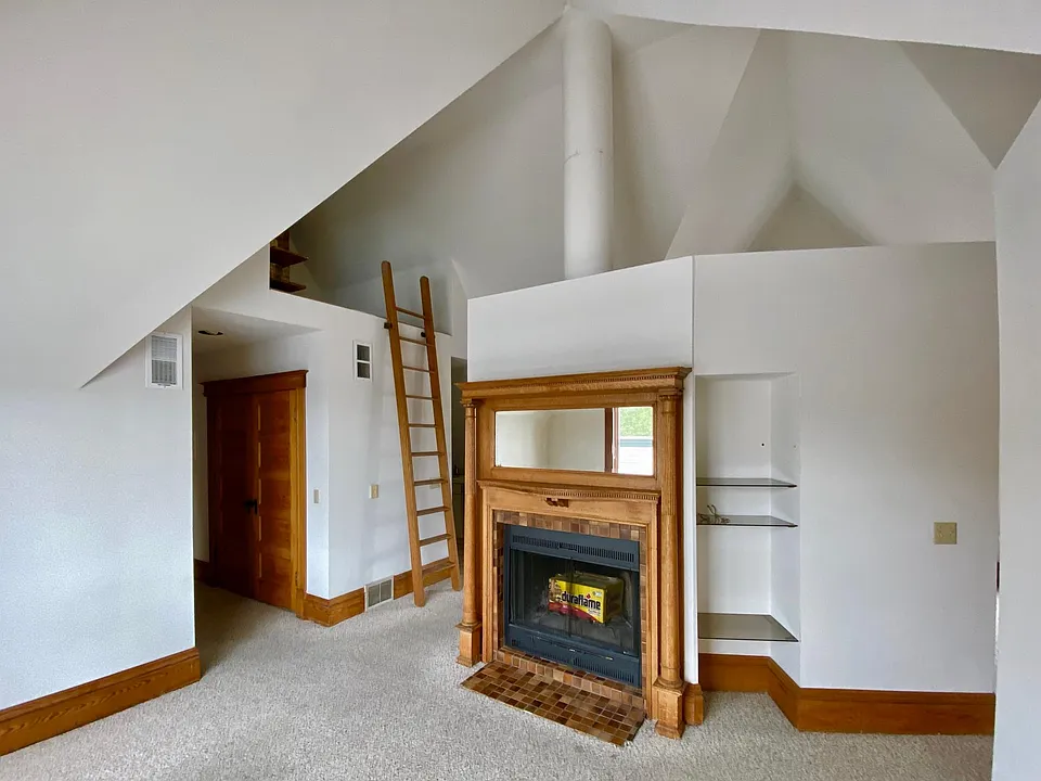 Living room w/fireplace and ladder to loft. Hall to left has laundry closet; leads to bath, bedroom