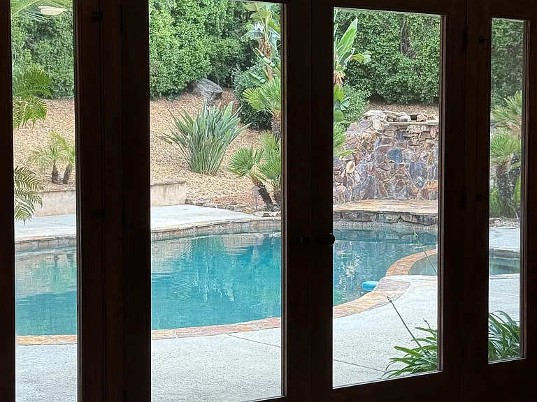 View of the backyard, pool, spa, and waterfall from this living space!