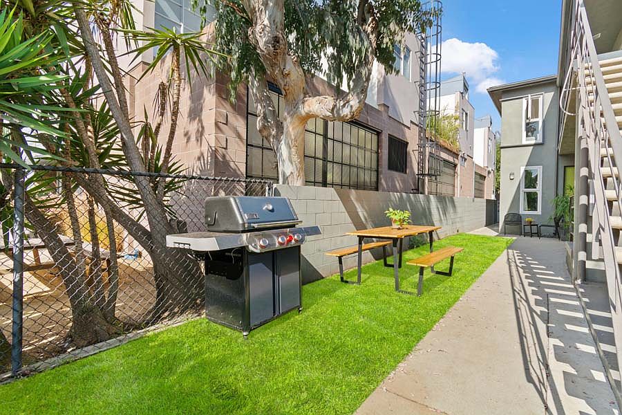 Side yard with picnic table and grill is a shared space.