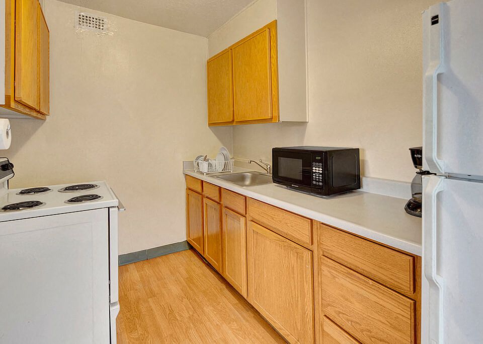 A kitchen with white appliances and wood cabinetry
