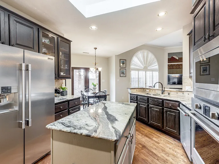 Kitchen features updated stainless steel appliances, dark brown cabinets, light hardwood / wood-style floors, light stone / granite type countertops, and tasteful backsplash. Refrigerator is included.