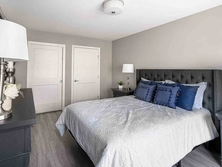 View of spacious bedroom with plank flooring, and doors to ensuite bathroom and walk-in closet