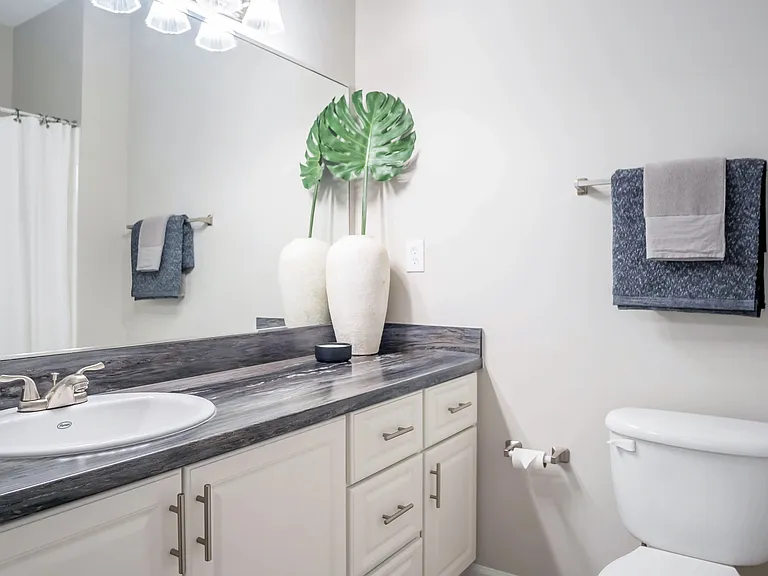 Our exquisite bathrooms feature black fusion countertops, expansive mirrors with vanity lighting, and luxurious tile flooring.