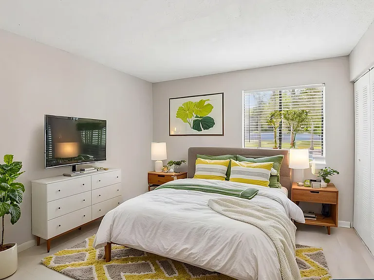 Inviting bedroom with plush bedding, vibrant decor accents, and large windows bringing in natural light, ideal for relaxation.