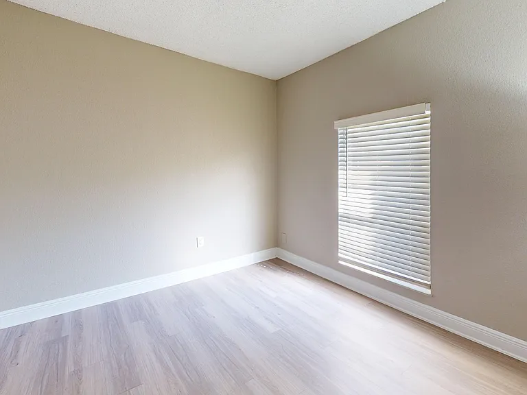 Bright and inviting empty room with modern wood flooring and a sunlit window, perfect for personalization and creativity.