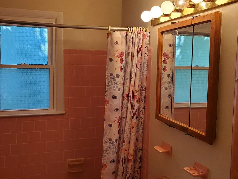 Room 2 -Private Full bathroom with a tub/shower combo, vanity sink, mirrored medicine cabinet, and a window for ventilation.