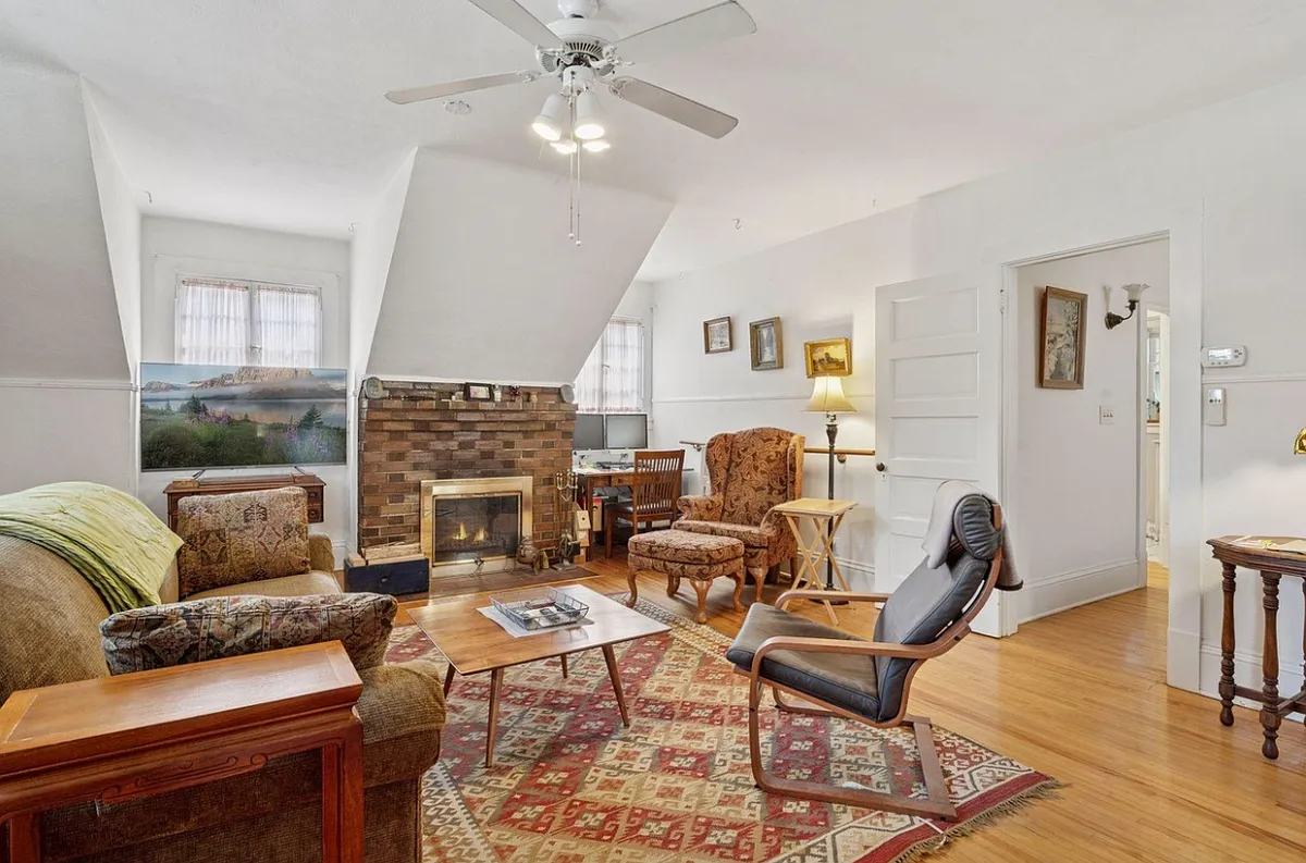 Bright living space - with active, functional wood-burning brick fireplace, north + south + east facing windows for tons of natural light, ceiling fan for well circulated air, and plenty of space for hosting, dining, exercise, working, etc. - 2601 Portland Ave #3
