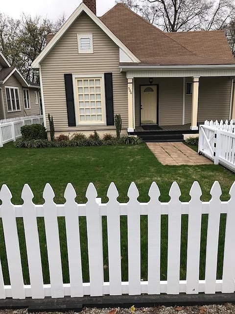 Front of house. White picket fence across all of front yard.