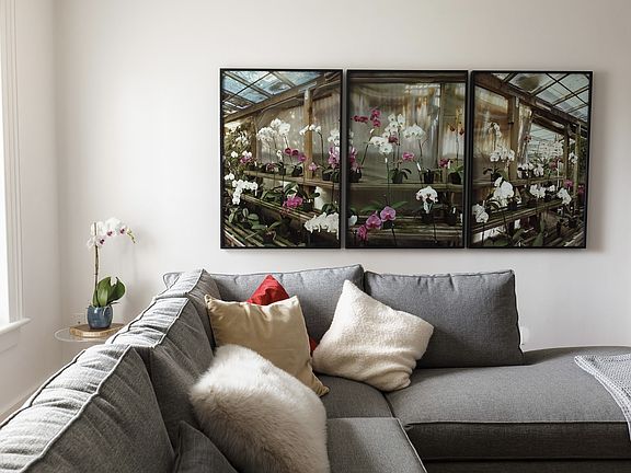 Living room - large triptypch photographs of greenhouse orchids above sectional sofa.