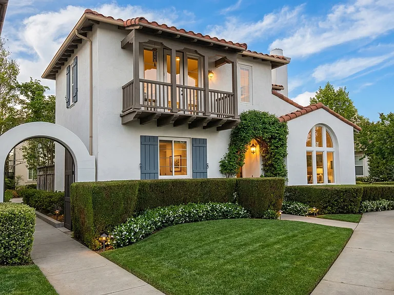 Stunning Spanish-style exterior with balcony, manicured landscaping, and prime location in gated Woodlands community