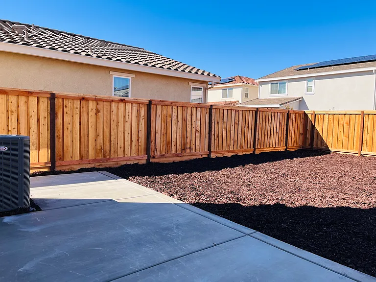 Backyard with extended concrete and low maintenance mulch