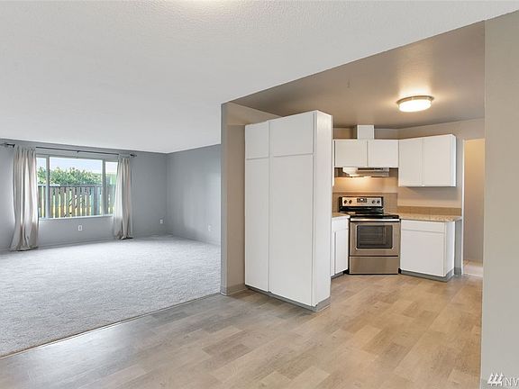 The interior of this home has been freshly painted in a gorgeous gray, and also features all new flooring. From the dining room you can see into the spacious living room and kitchen. You'll enjoy extra storage in the tall pantry cabinets here.