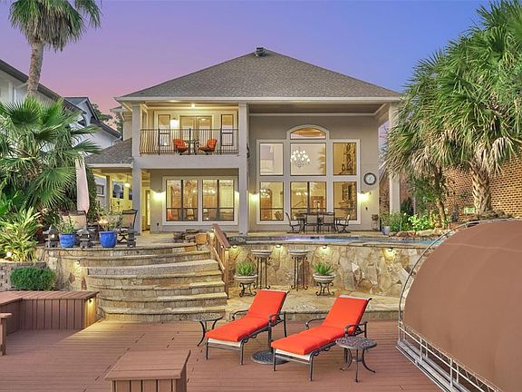 Large entertaining backyard with heated beach entry pool, soaring 2 story covered porch, detailed landscaping, summer kitchen and large deck space.