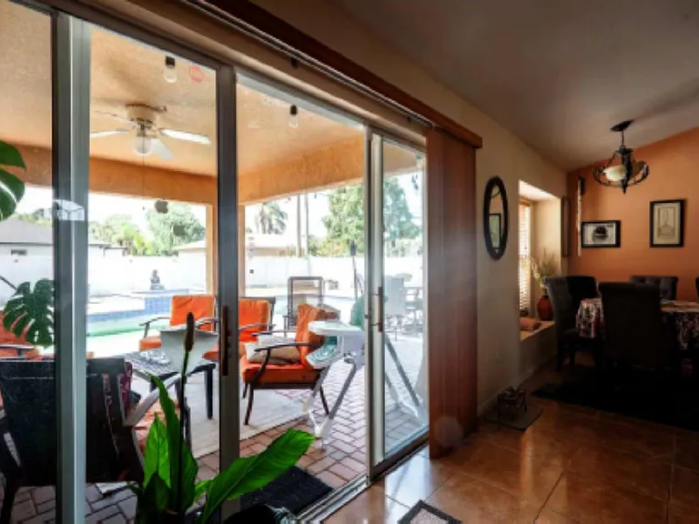 Dining area with sliding glass doors opening to a covered patio and pool, providing an easy indoor-outdoor flow.