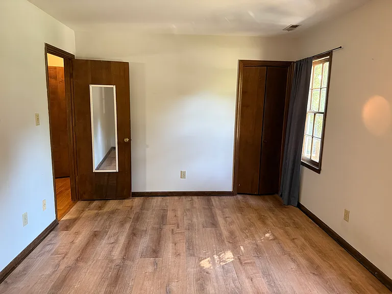 Bedroom looking out to the front of the unit; LVP flooring and two windows.