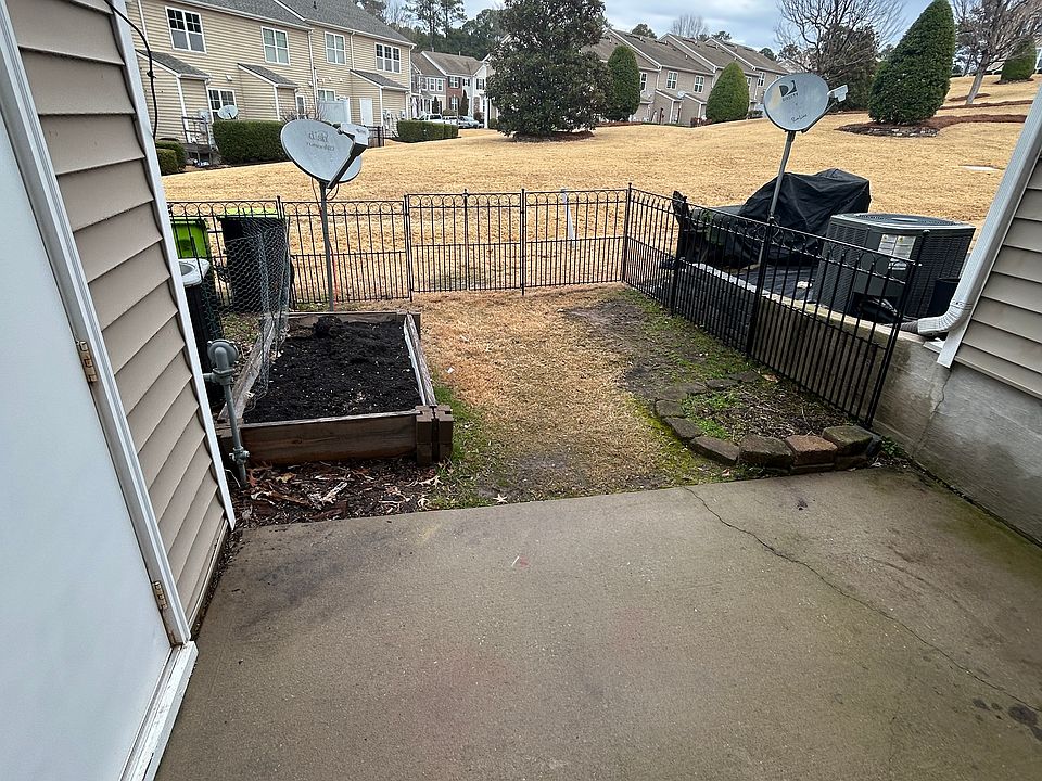 Fenced back patio with small yard and garden box overlooking common green space