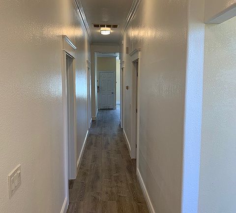 Main Hallway From Entry POV. New LVP wood-style flooring installed throughout the home & Vaulted 12-foot ceilings throughout.