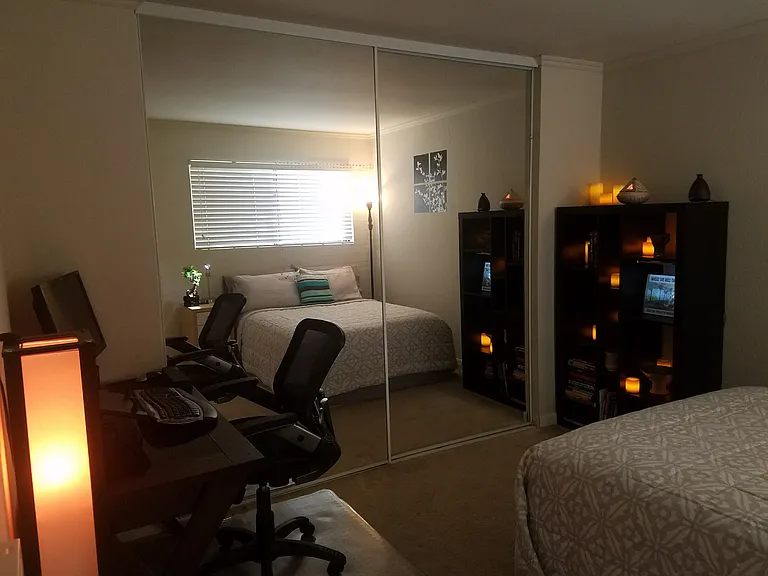 View of bedroom with queen bed, large desk, large book shelf